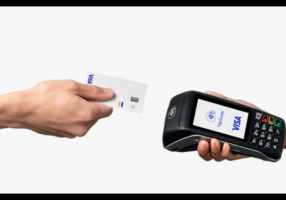 Business owner holding personal credit card next to tax documents and laptop